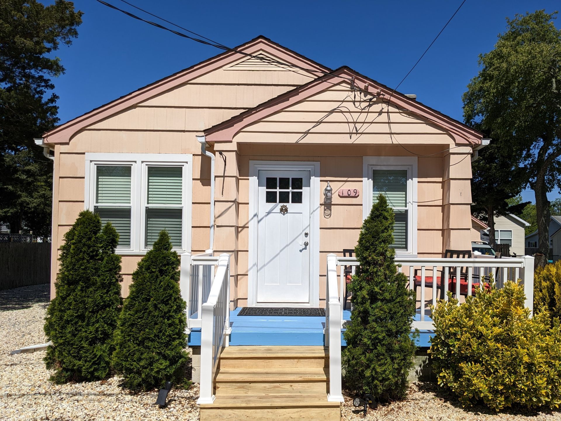 A small pink house with a white door and stairs