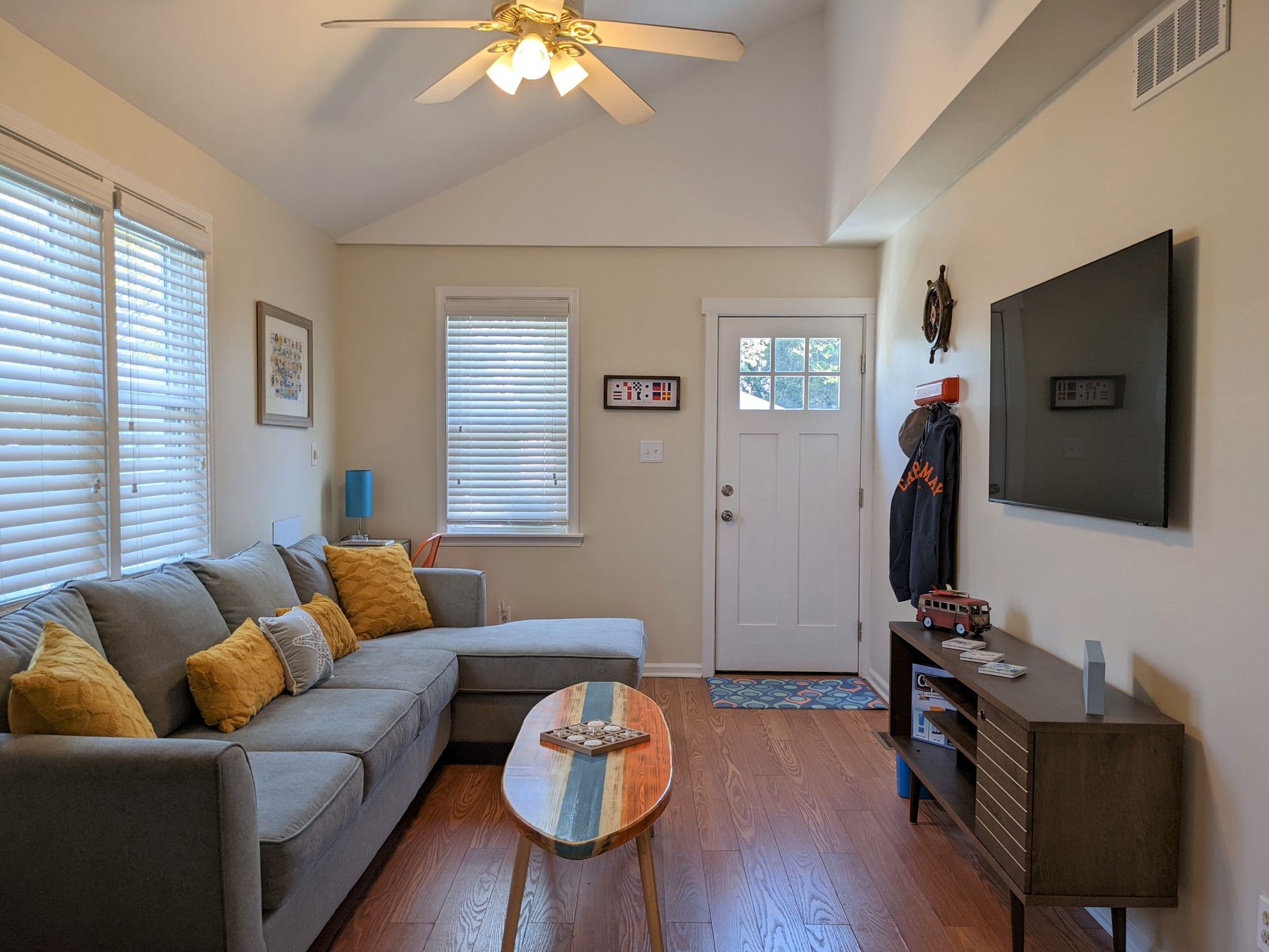 A living room with a couch , table , television and ceiling fan.