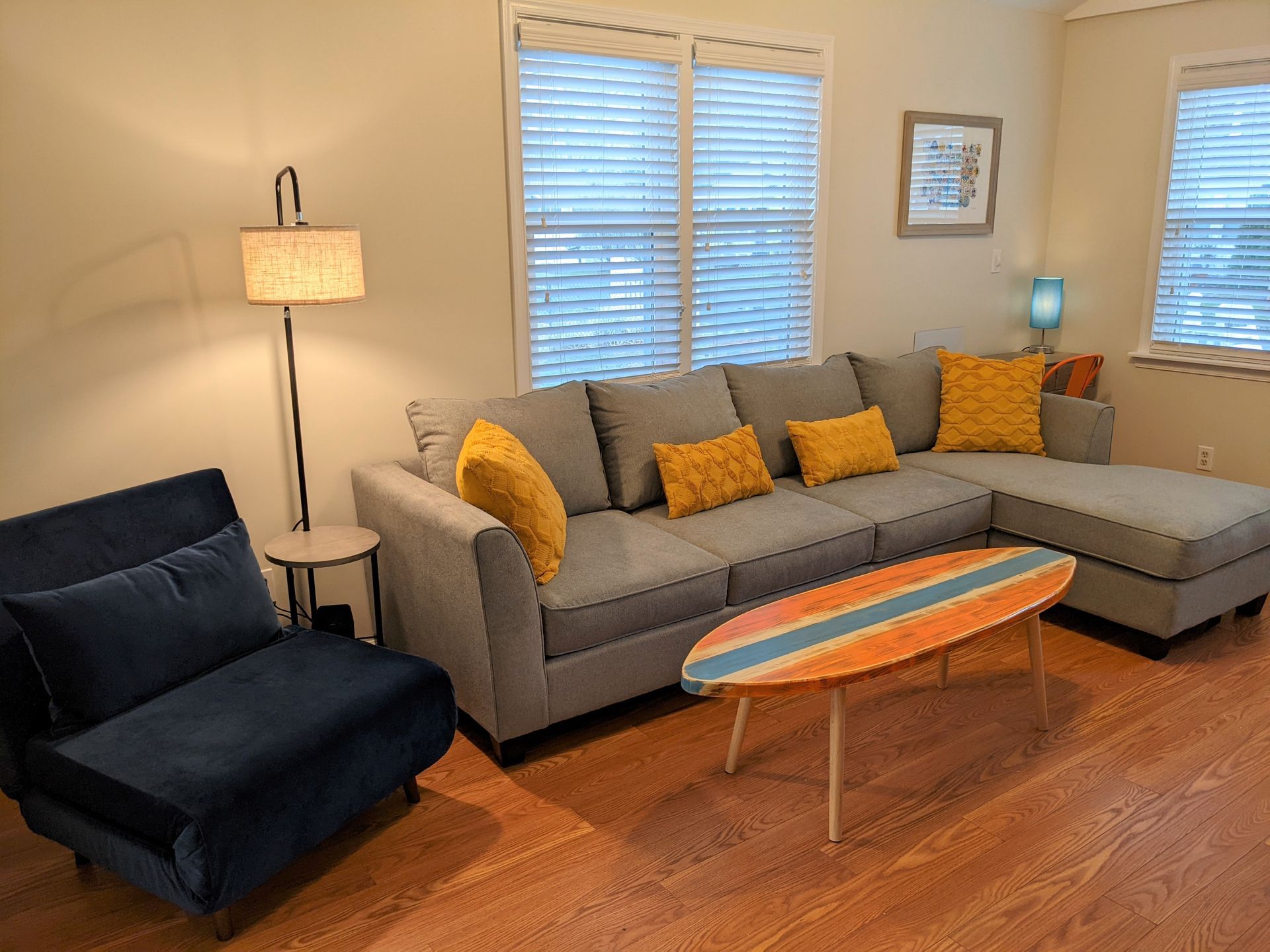A living room with a couch , chair , coffee table and surfboard table.