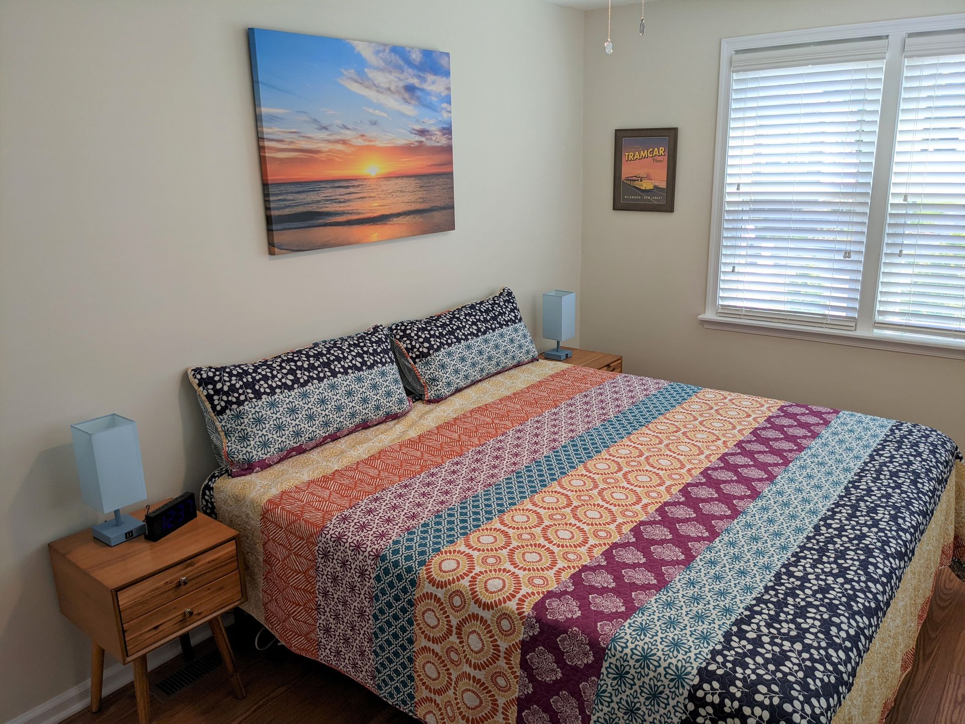 A bedroom with a large bed and a painting on the wall above it.