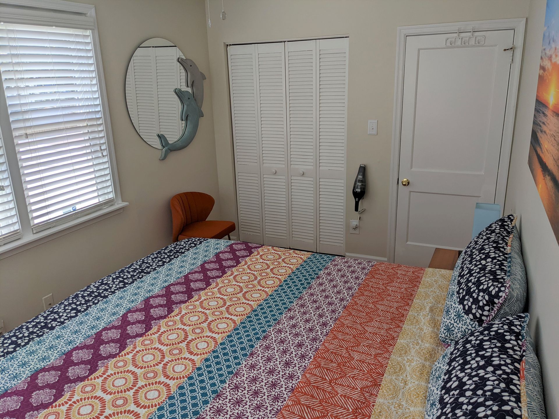 A bedroom with a bed , chair , mirror and closet.