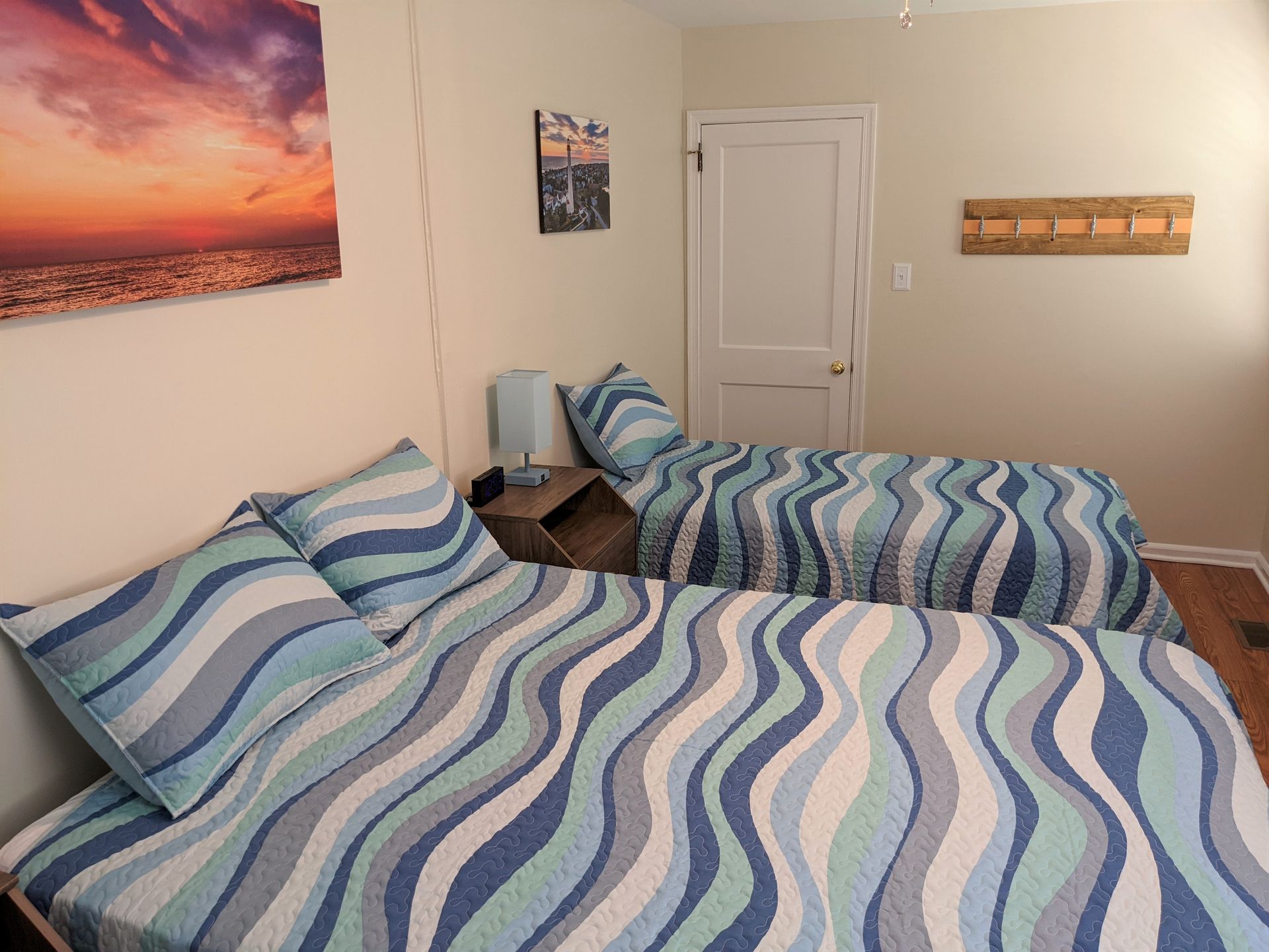 A bedroom with two beds and a painting on the wall