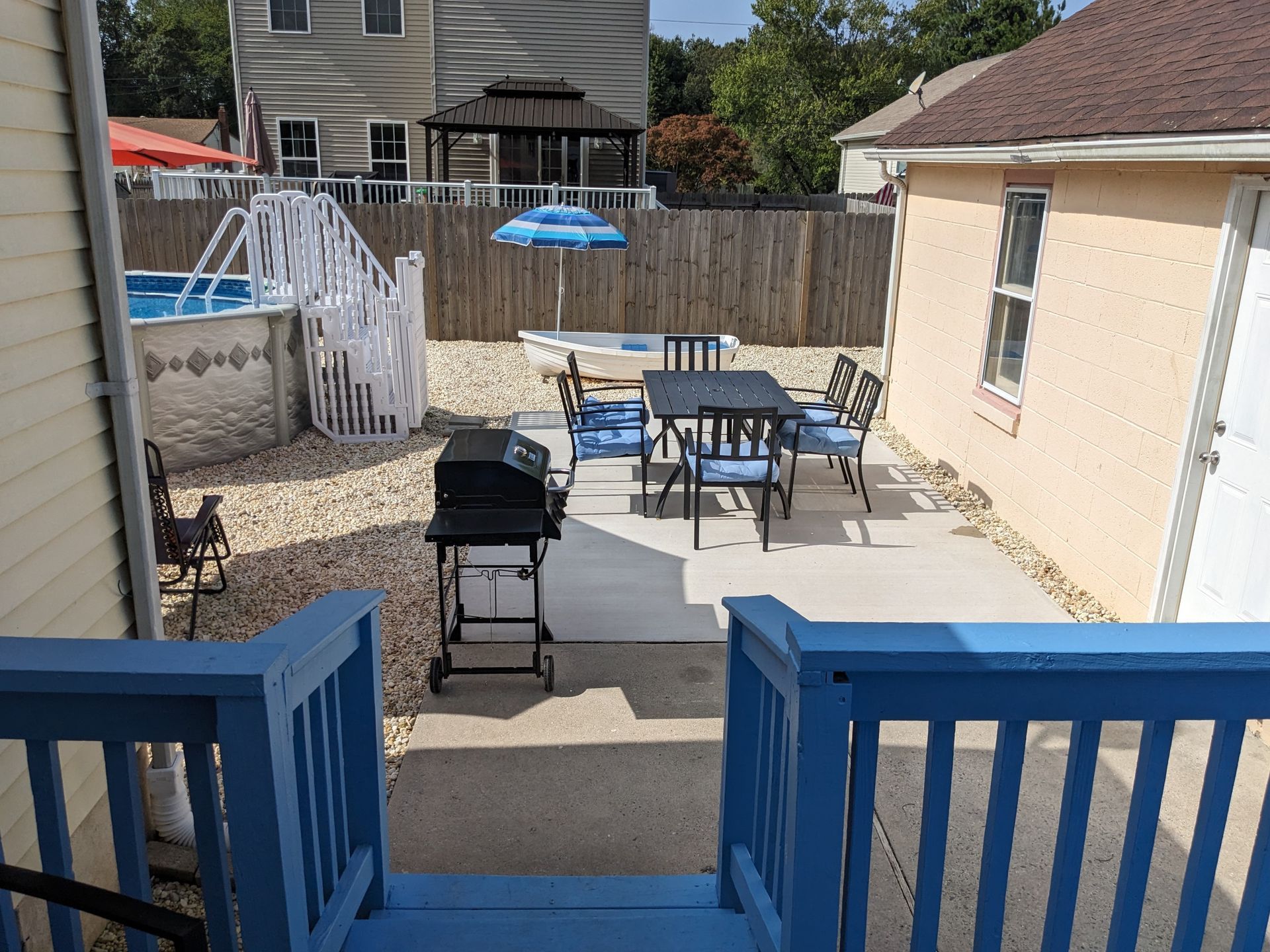 The backyard of a house with a table and chairs and a grill.