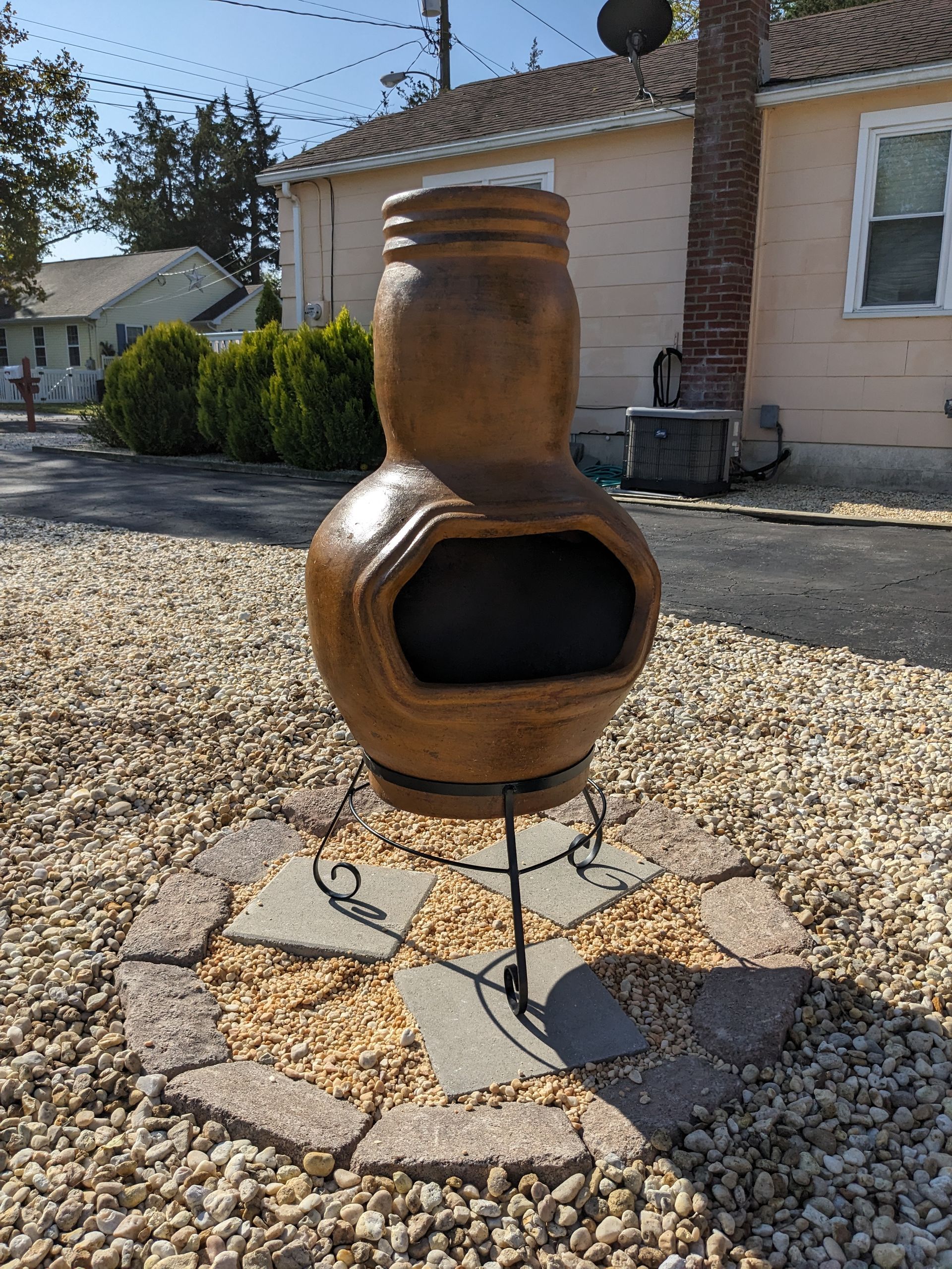 A fire pit in a gravel area in front of a house