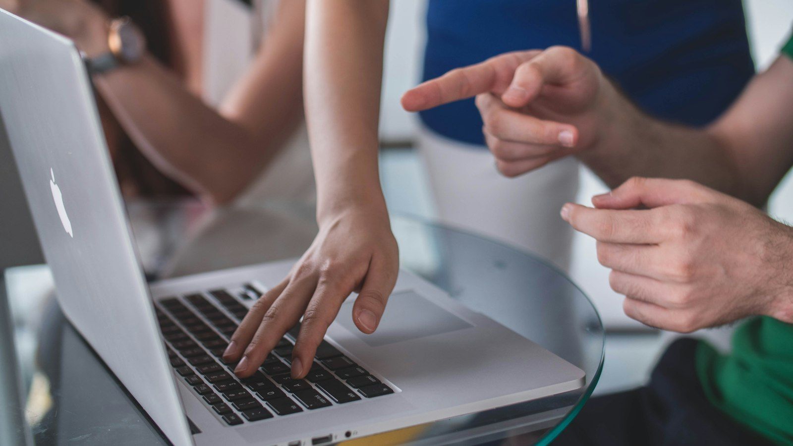 Hands pointing at a laptop while someone types, suggesting a collaborative discussion.