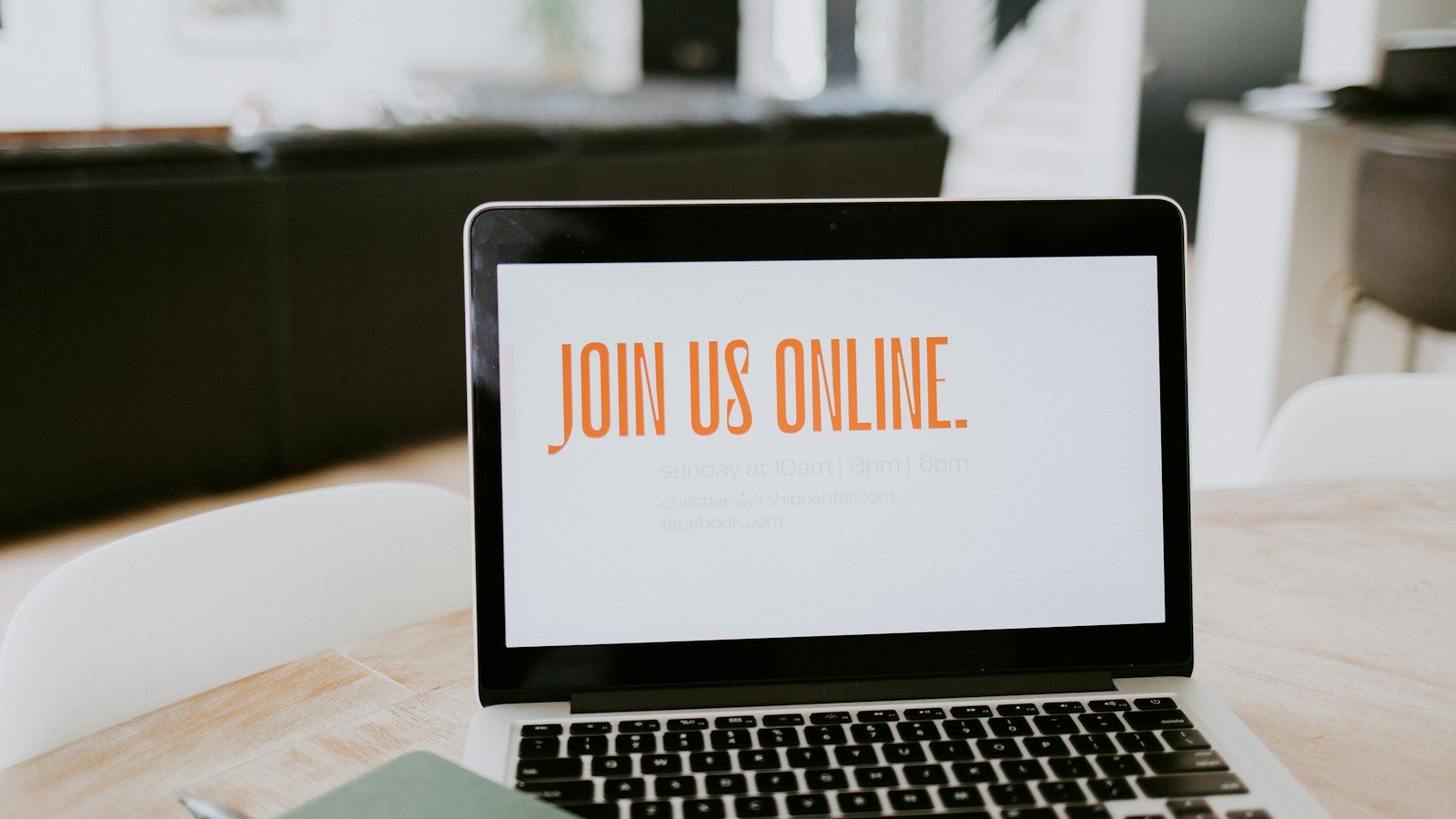 Laptop screen with “JOIN US ONLINE” on a desk in a bright office.