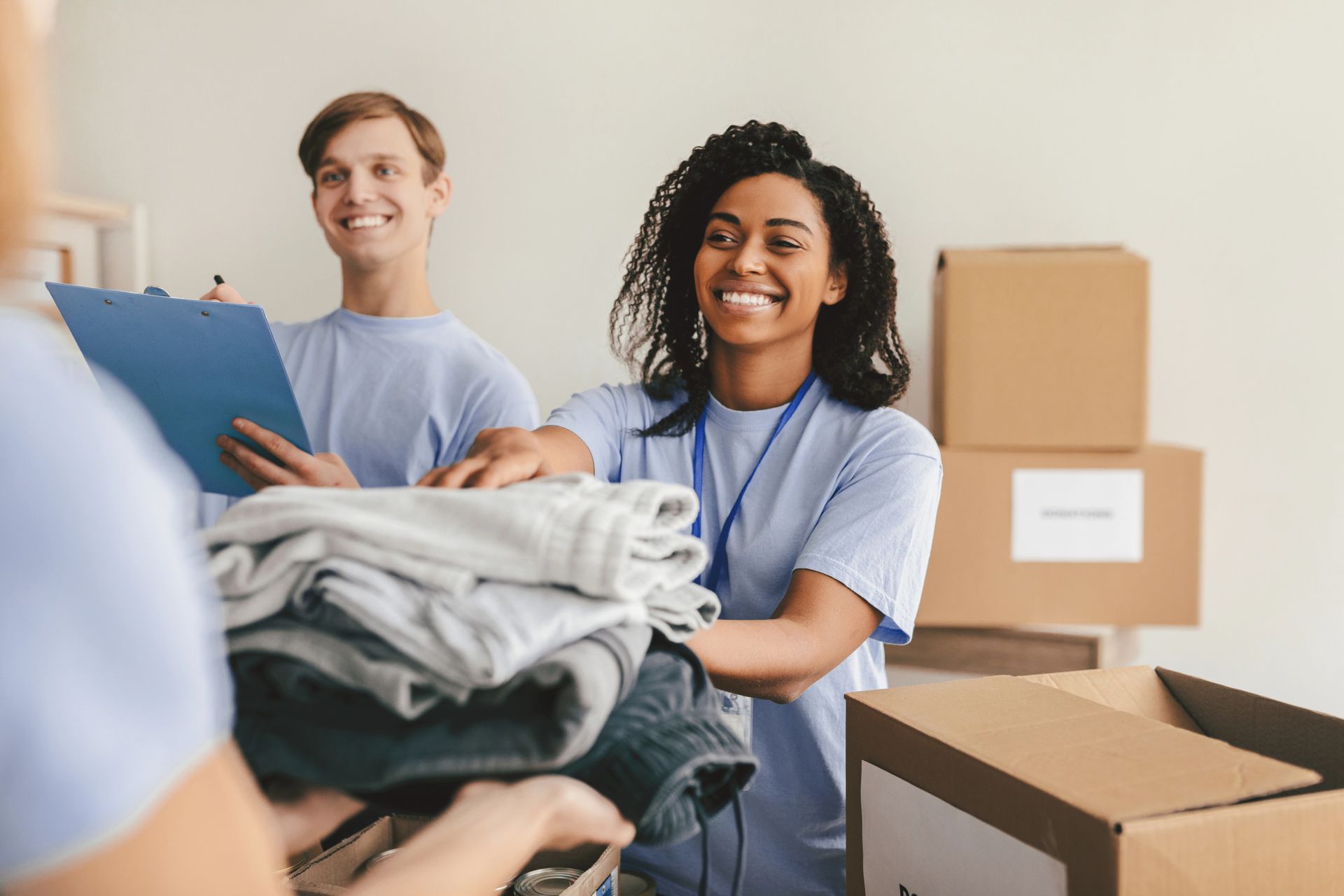 Volunteers sorting folded clothes into boxes in a donation room