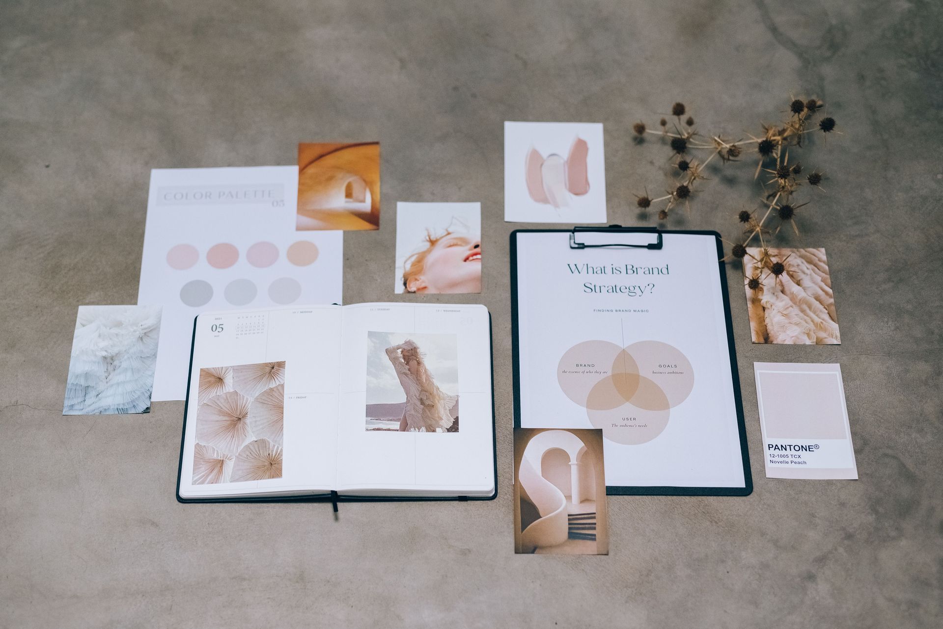 Flat-lay of wedding stationery, invitations, floral prints, and gold decorative accents on a gray floor