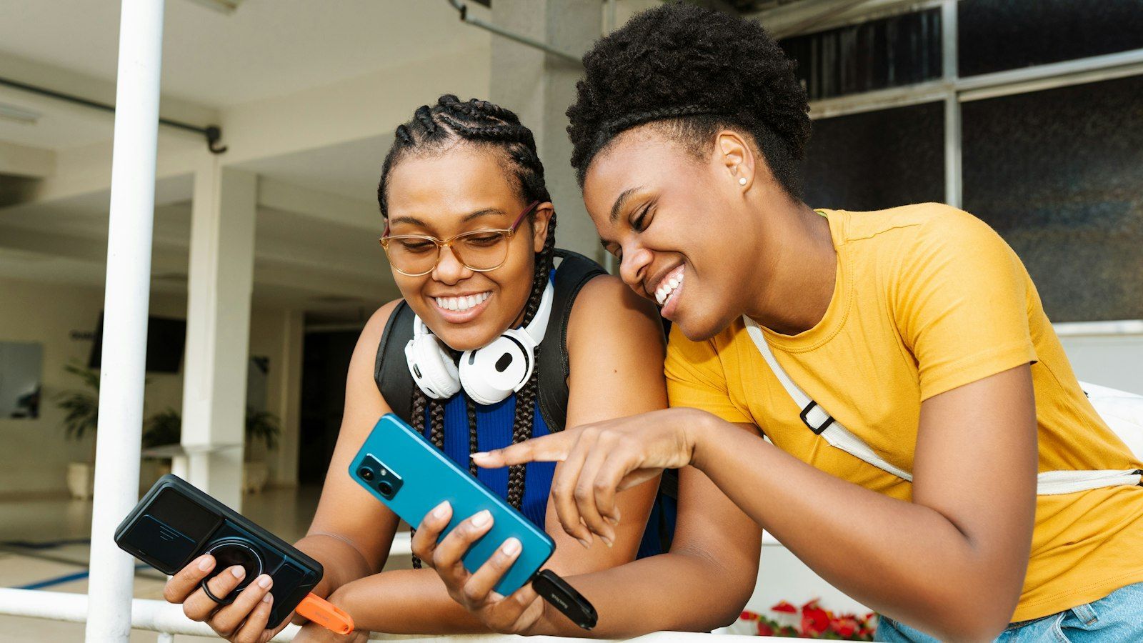 Two friends smiling on a couch, looking at their phones together in a bright living roomPhoto by Sandisk on Unsplash
