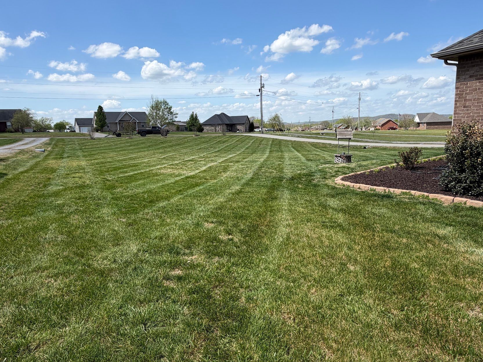 Lawn sprinklers spraying water along a suburban row of houses and a sidewalk