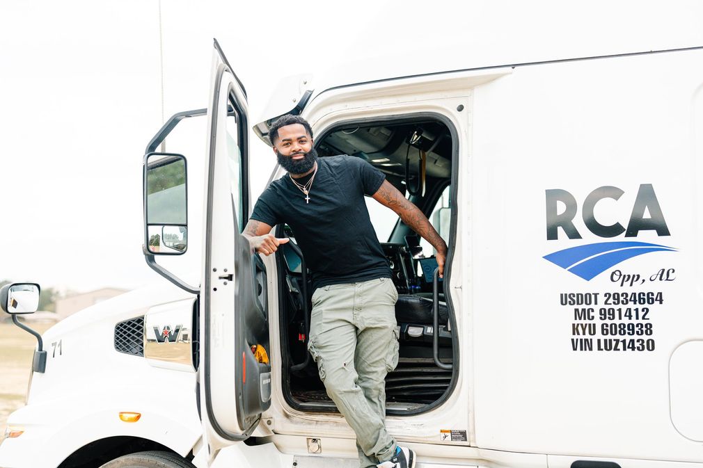 A person standing in the open door of a white semi-truck with 