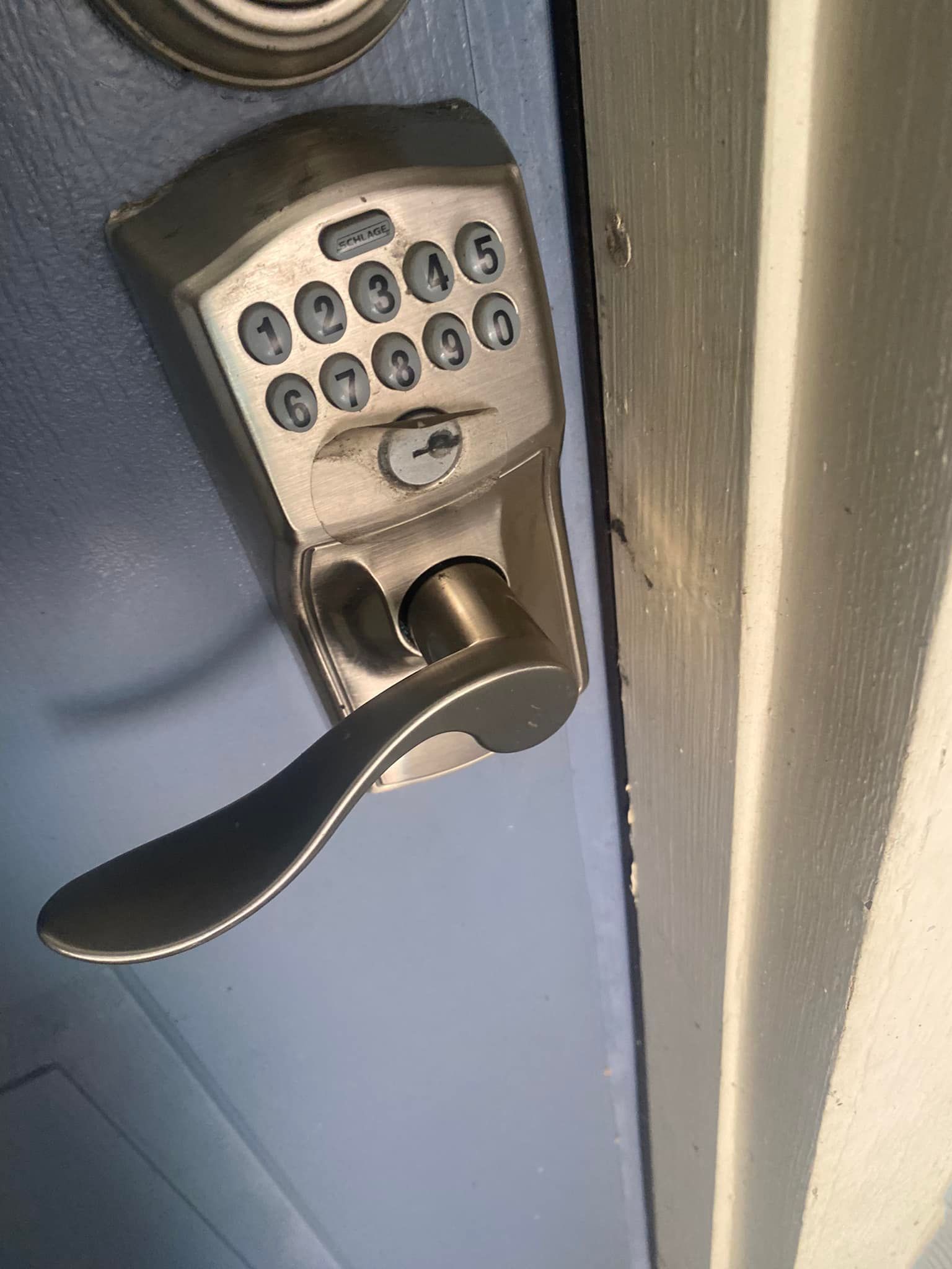 Digital keypad door lock with handle on a blue door.