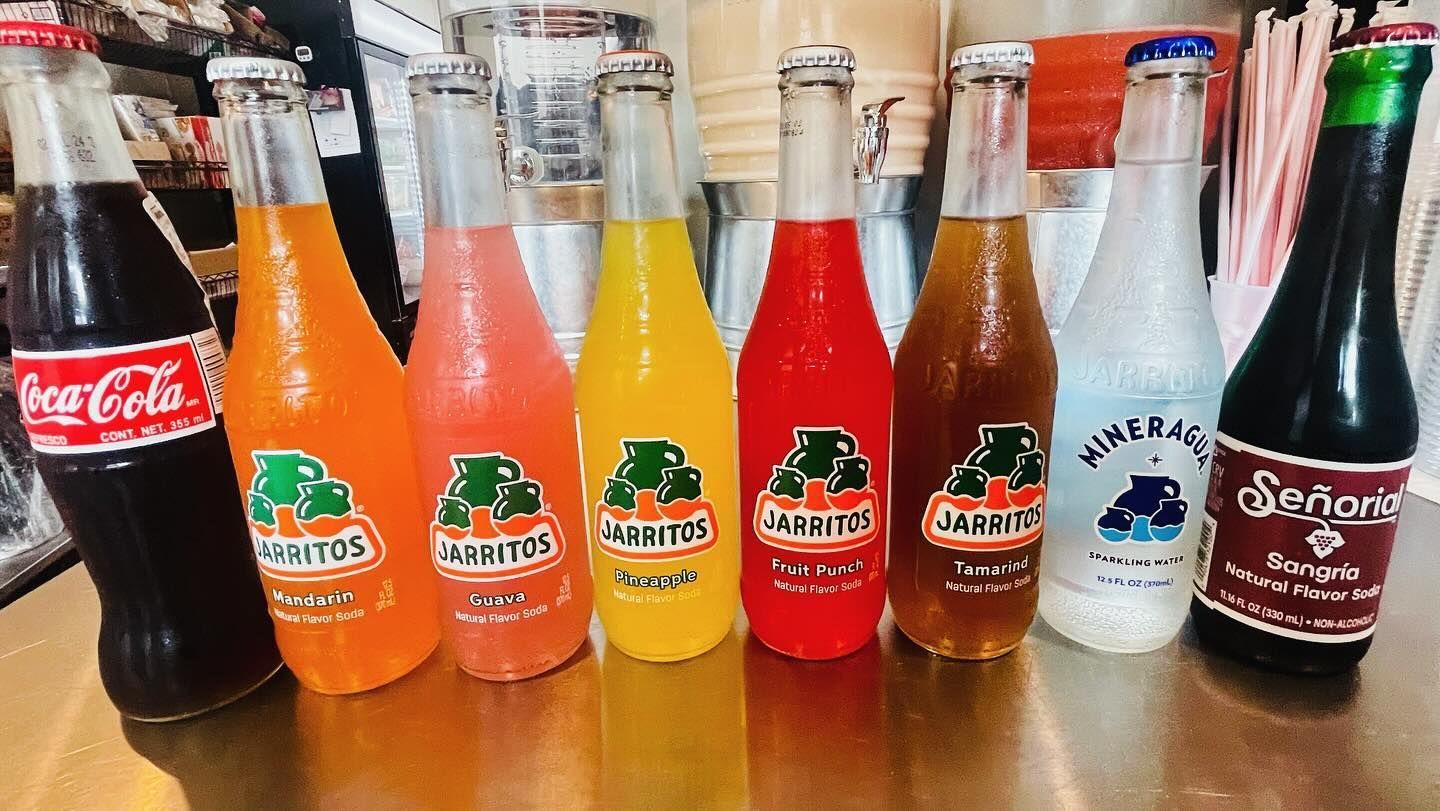 Assorted soda bottles in a row, including Coca-Cola, orange sodas, root beer, and ginger ale.