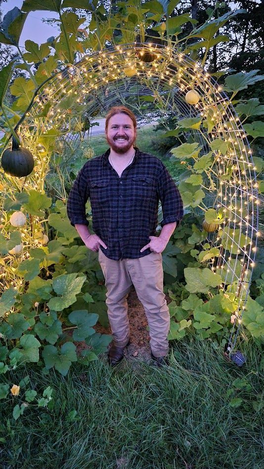 man stands beneath the Ostara's Grove Pumpkin Trellis Lunenburg, Vermont