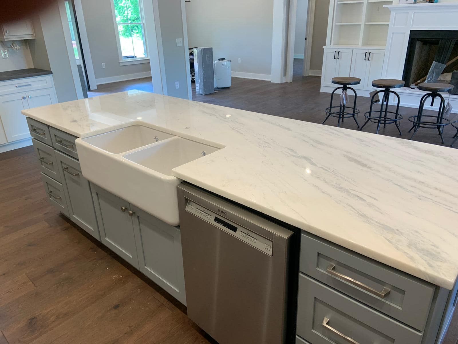 Modern kitchen island with sink, dishwasher, and marble countertop in a bright open-plan home.