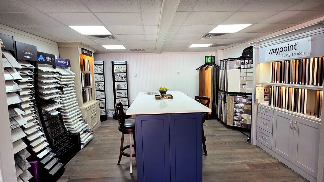 Flooring showroom with display racks, sample boards, and a central table on a white floor.