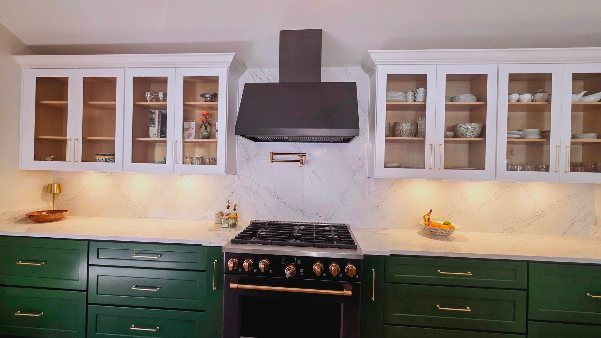 Green and white kitchen with a stove, cabinets, and range hood.