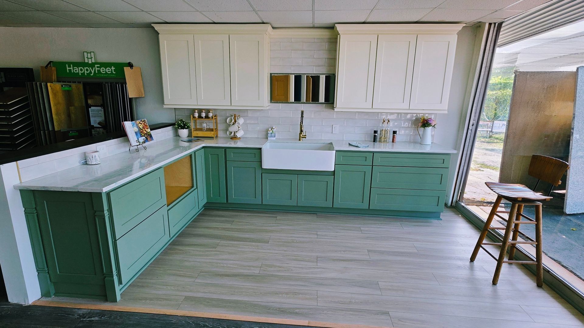 Bright kitchen with mint cabinets, white upper cabinets, open shelves, and a stool by the window.