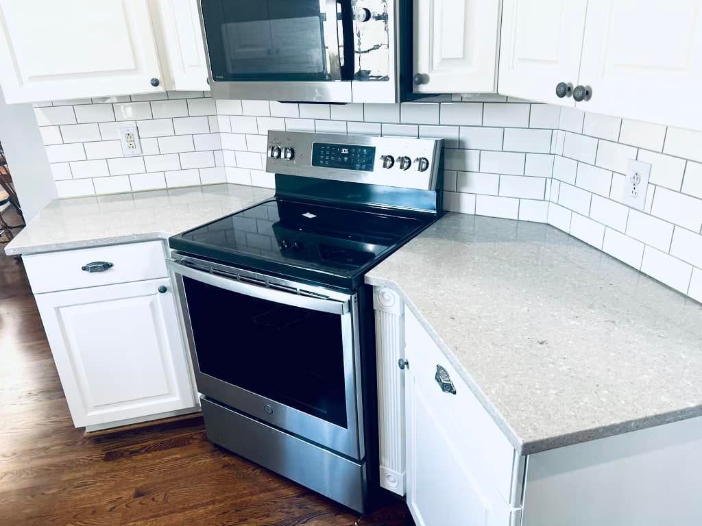 A kitchen with a stove , microwave , and white cabinets.