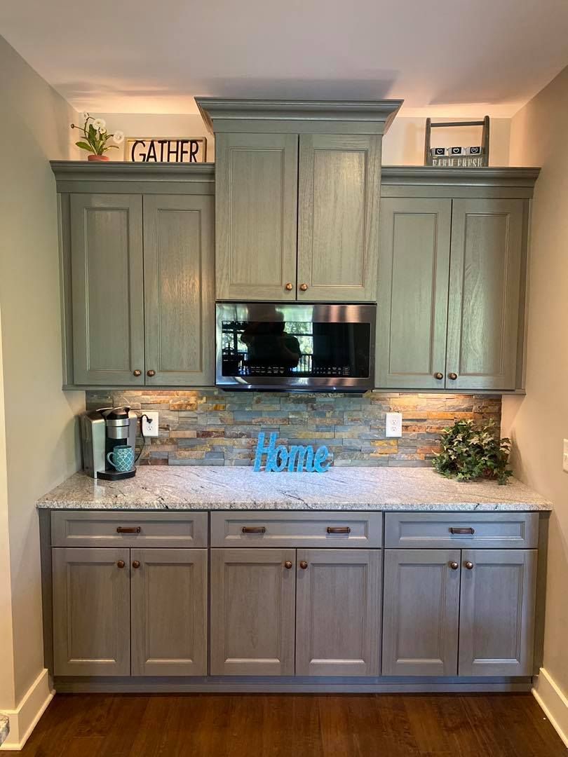 A kitchen with gray cabinets and granite counter tops.