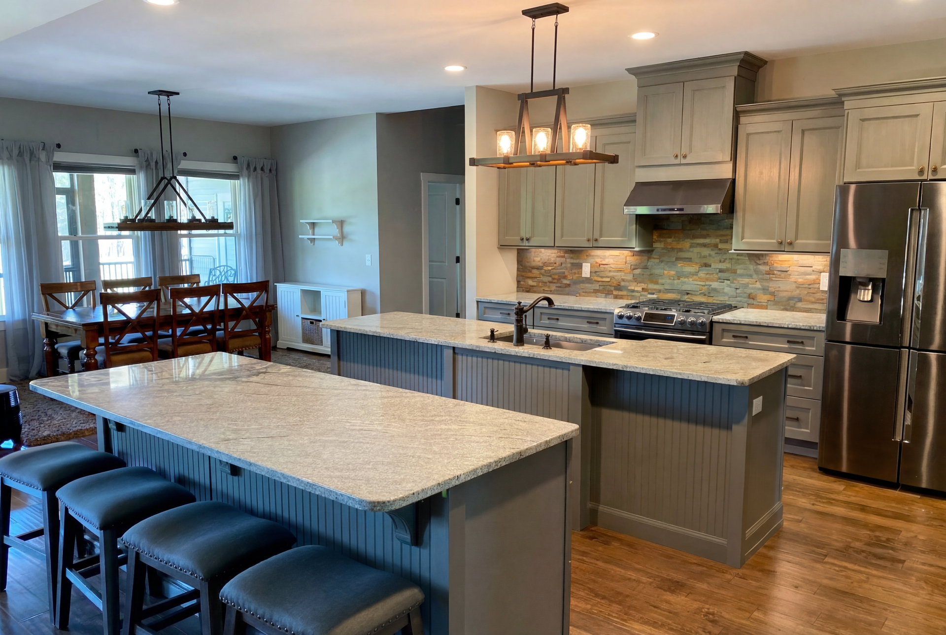 Modern kitchen with large island, gray cabinets, stainless steel appliances, and adjacent dining area