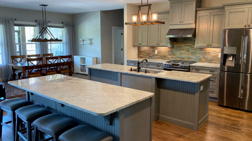 Modern open kitchen with island, pendant lights, stainless appliances, and dining area beyond.