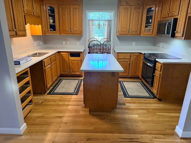 Kitchen with wooden cabinets, white countertops, central island, and a window over the sink.