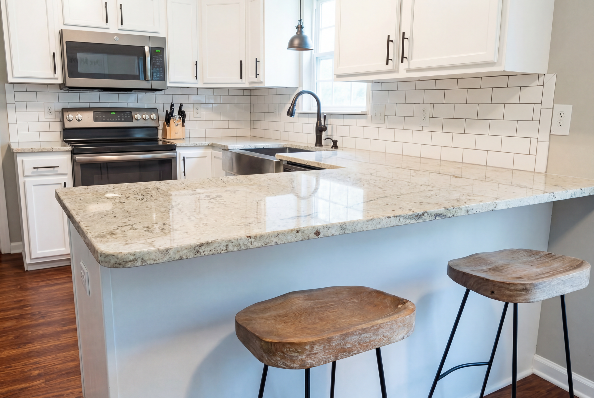 Kitchen with white cabinets, light countertops, and two wooden bar stools.