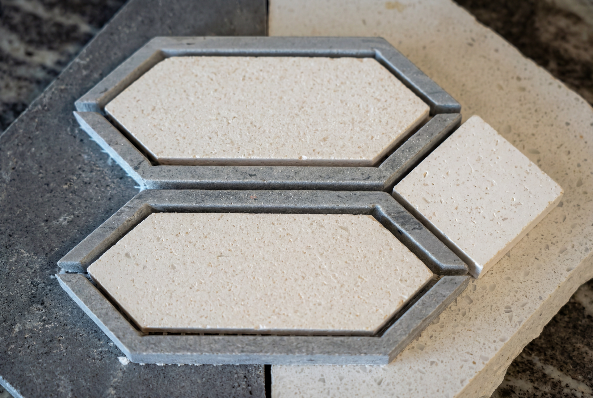 Close-up of tile samples: two hexagonal tiles with gray borders and white centers, plus a white square tile.