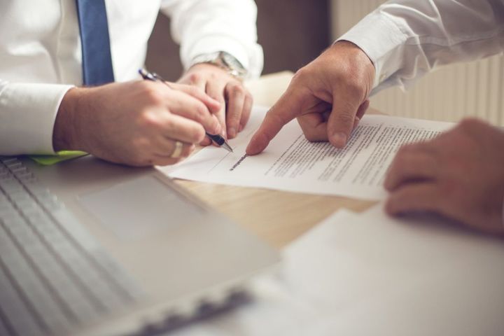 Uomo che firma dei moduli in compagnia di un avvocato