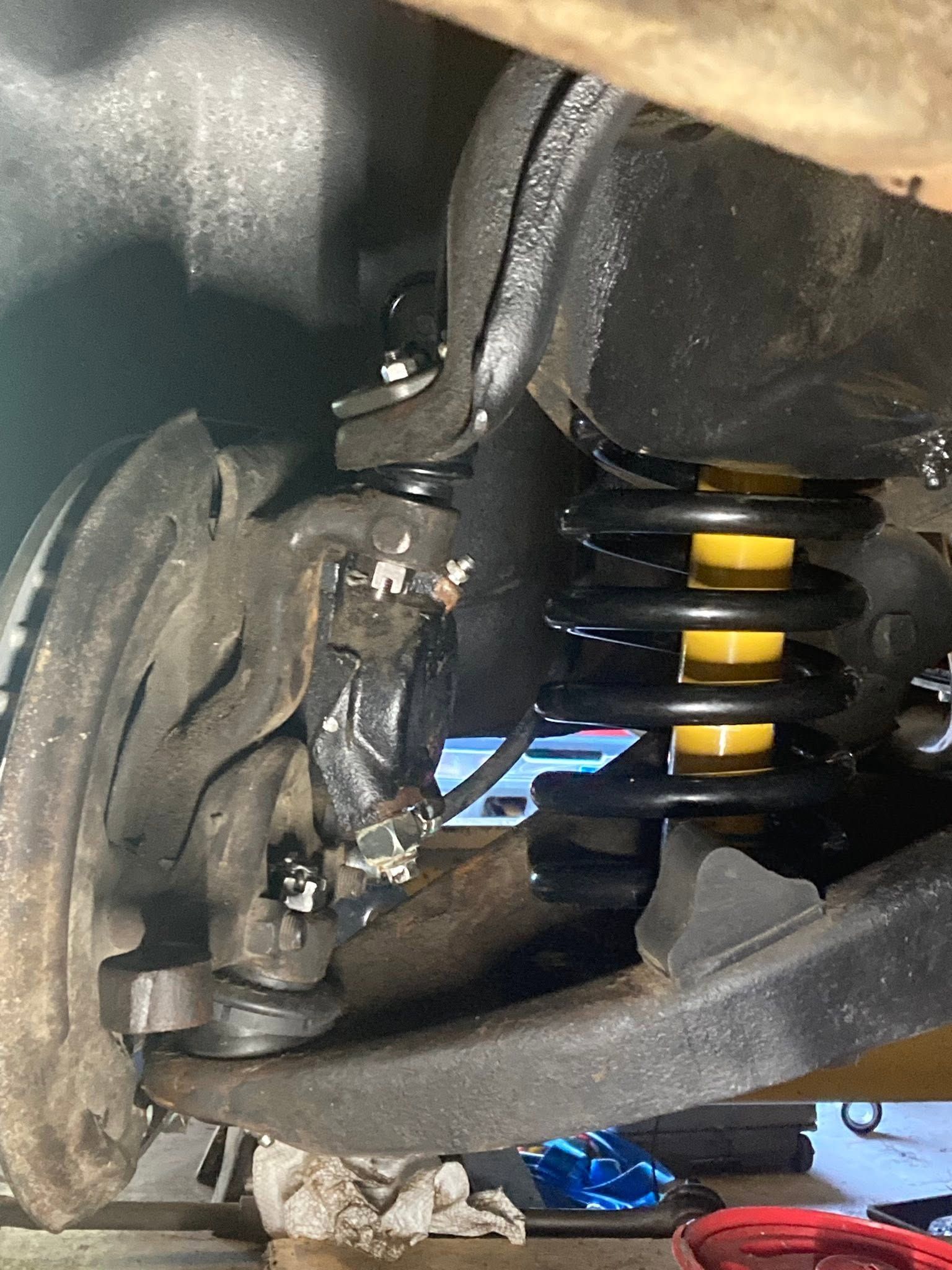 Close-up of a damaged car suspension with broken wheel hub and coil spring visible
