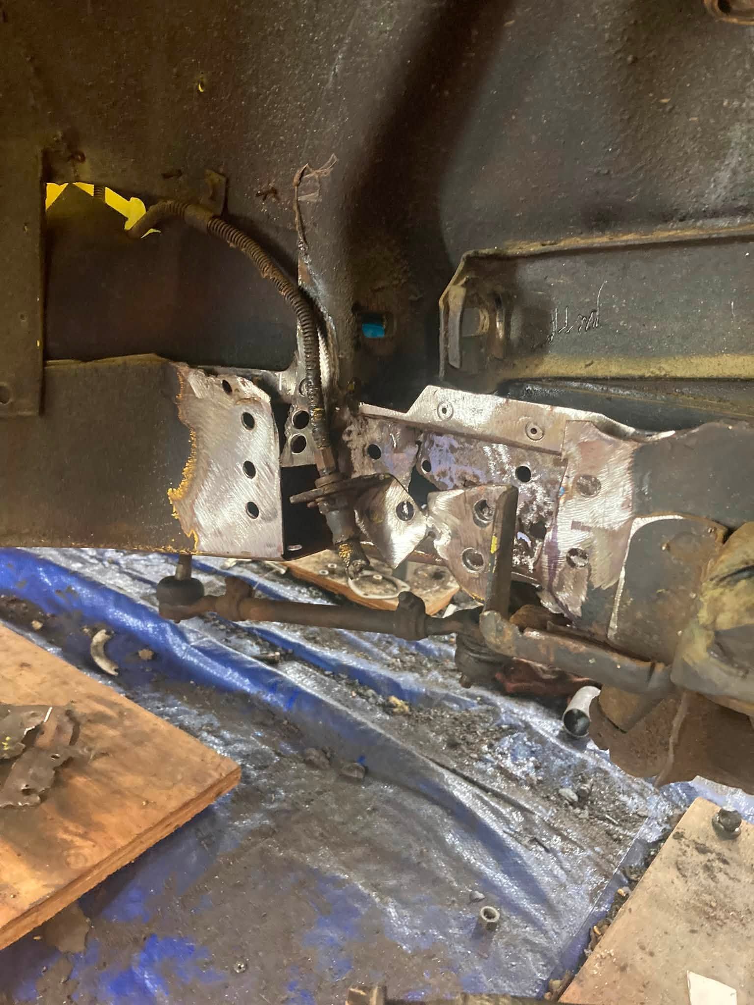 Damaged vehicle interior with exposed metal parts, blue tarp, and debris on the floor.