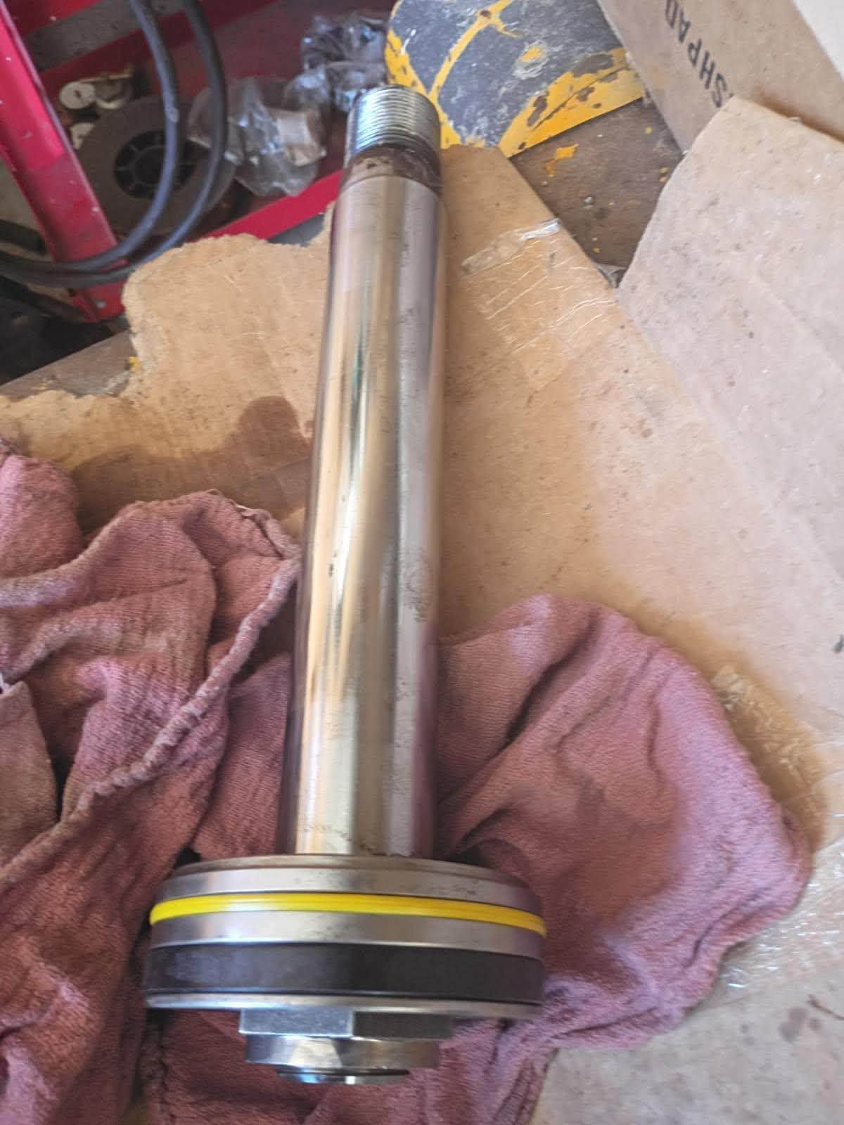 Metal automotive shaft with bearing on cardboard, beside a wrench and pink shop rag