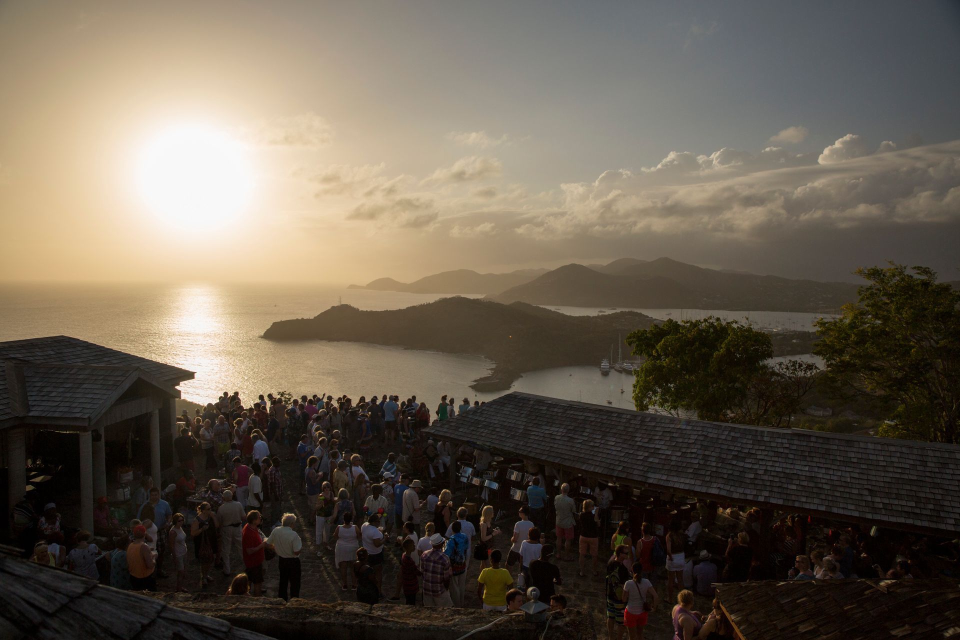 A large group of people partying on top of a hill overlooking Shirley Heights.