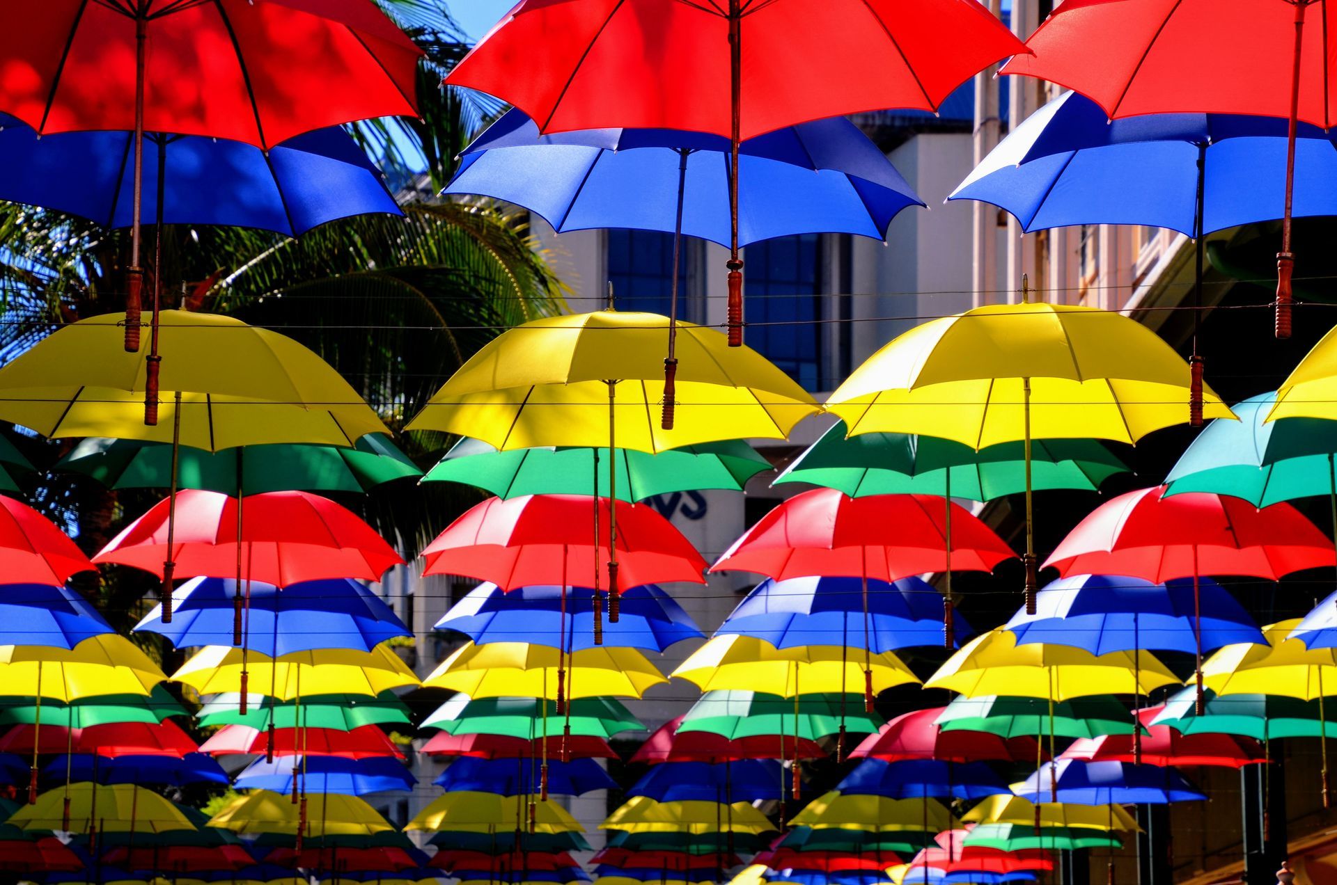 A bunch of umbrellas resembling the colours of Mauritian Flag are hanging from a pole on a street in Port Louis, Mauritius.
