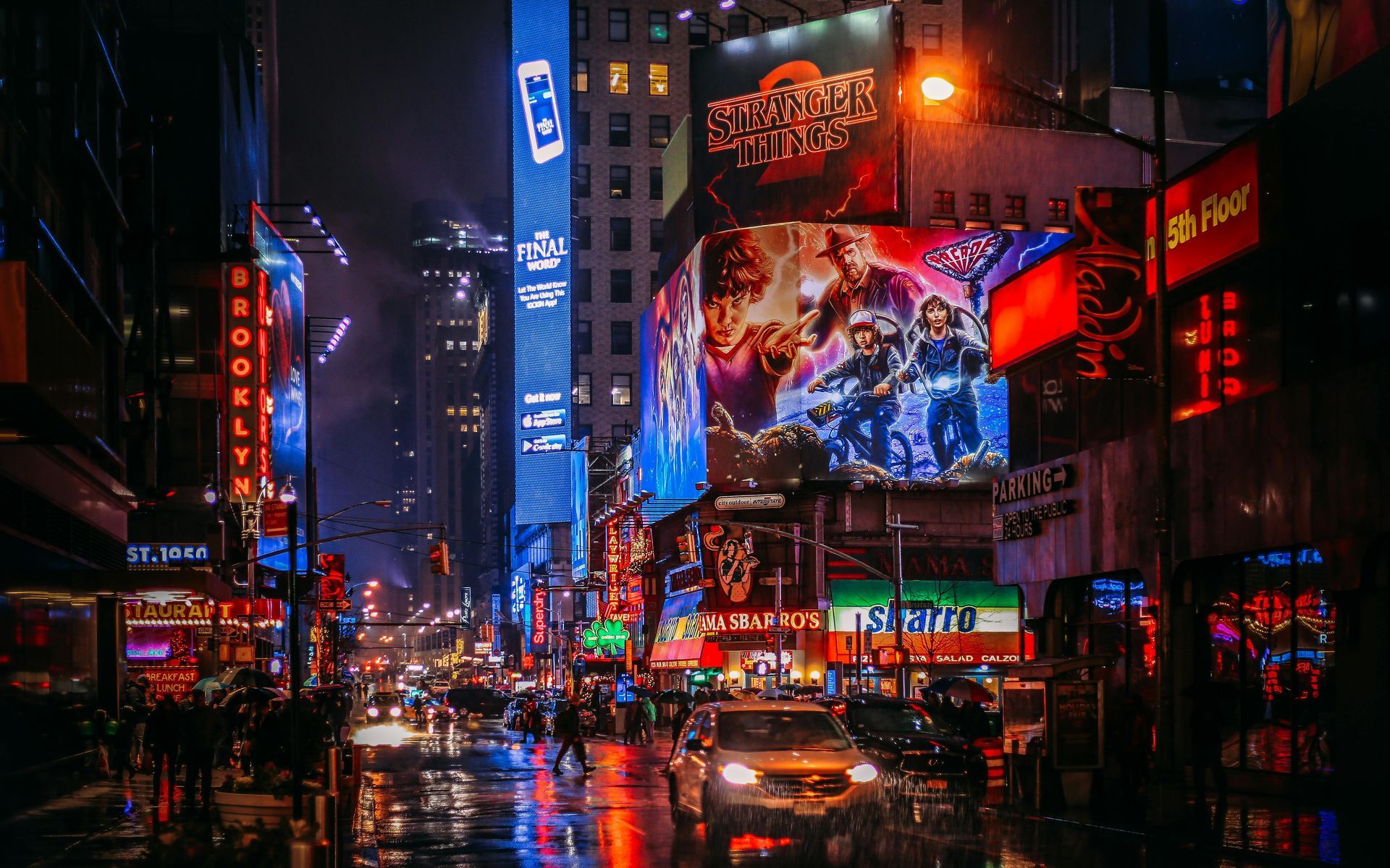 A busy New York city street at night with a lot of advertisements on the buildings.