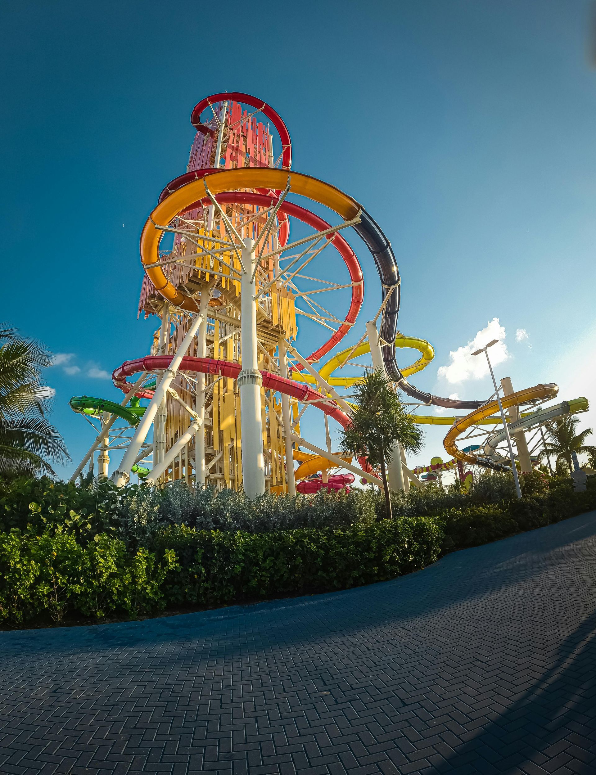 A tall water slide tower with colorful twisting slides against a clear blue sky.