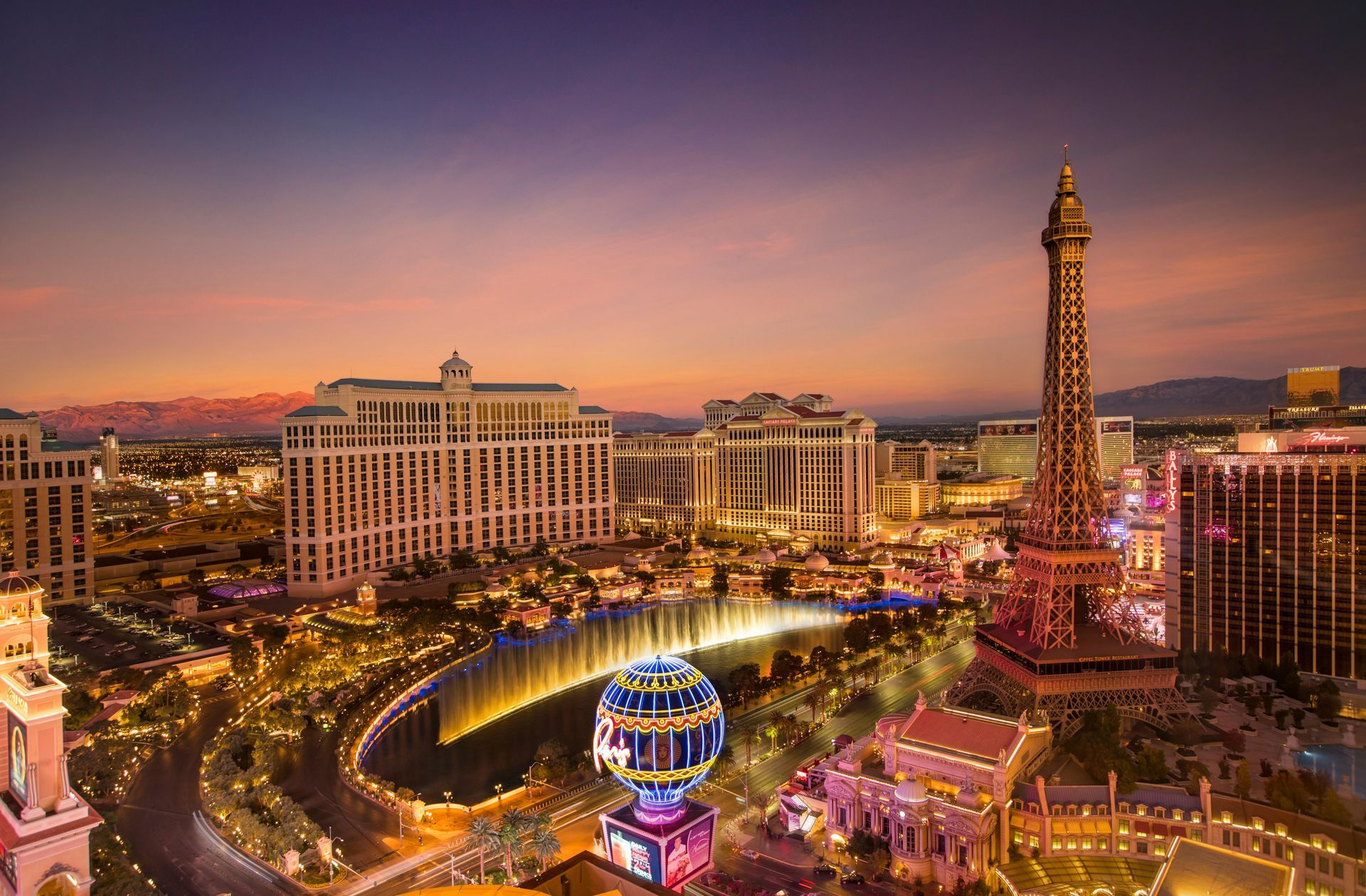An aerial view of Las Vegas at night with a waterfall and a ferris wheel.