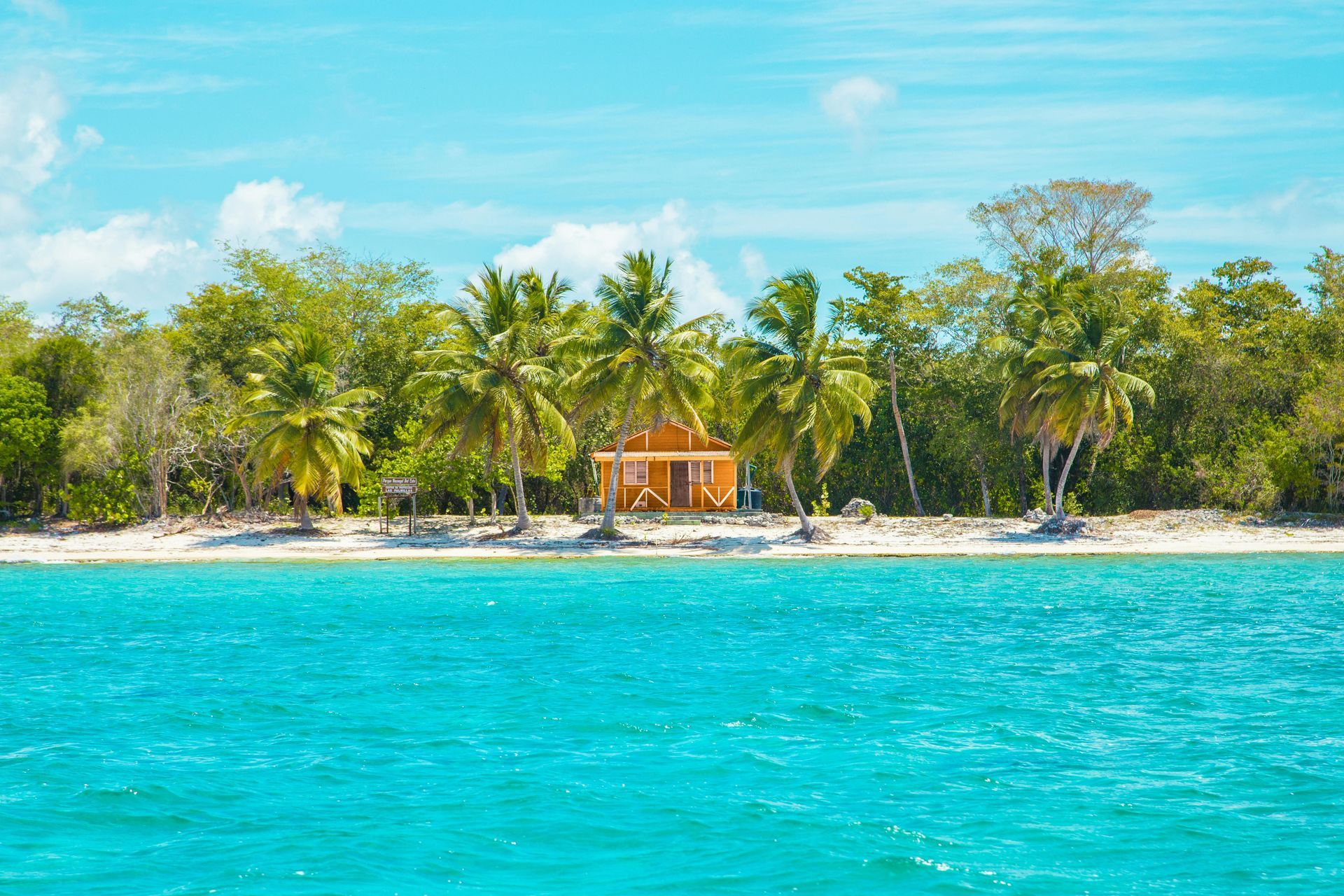 A small house is sitting on a small island in the middle of the ocean.