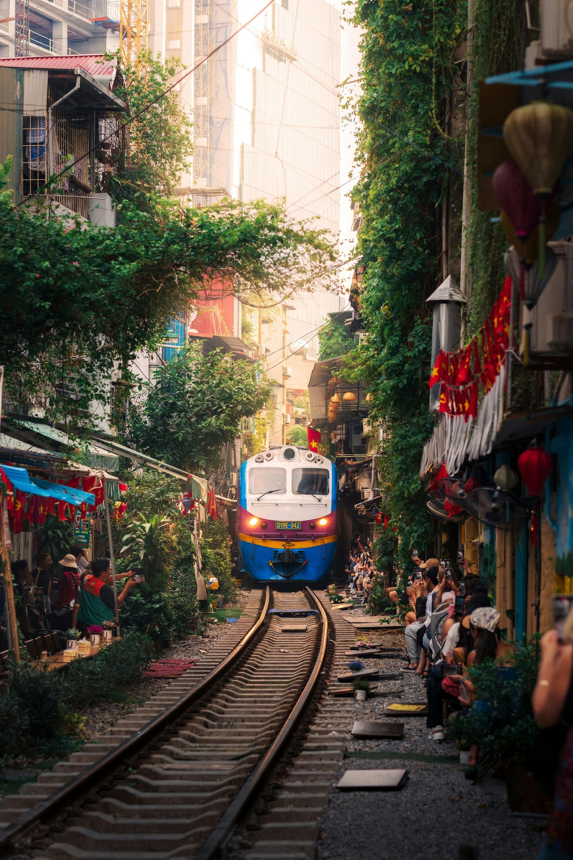 A train is going down train tracks in a narrow alleyway.