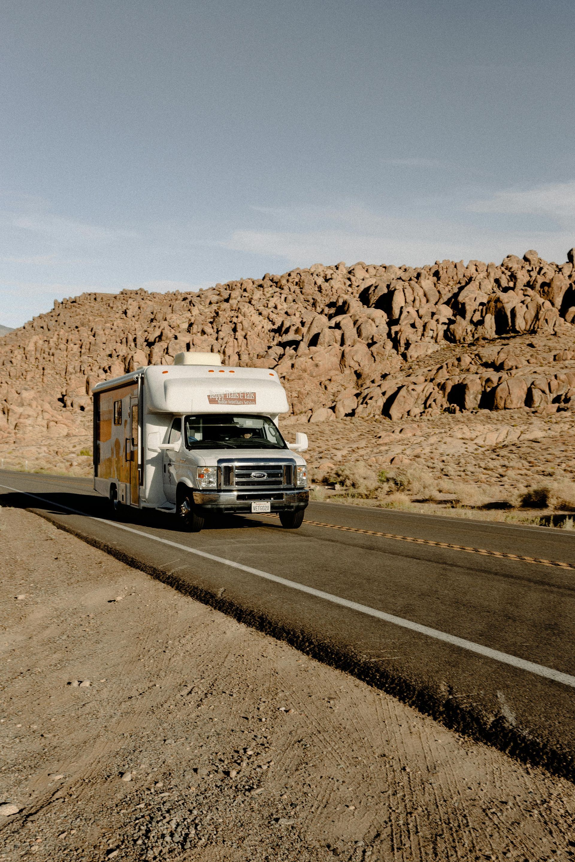 A rv is driving down a dirt road in the desert in the USA