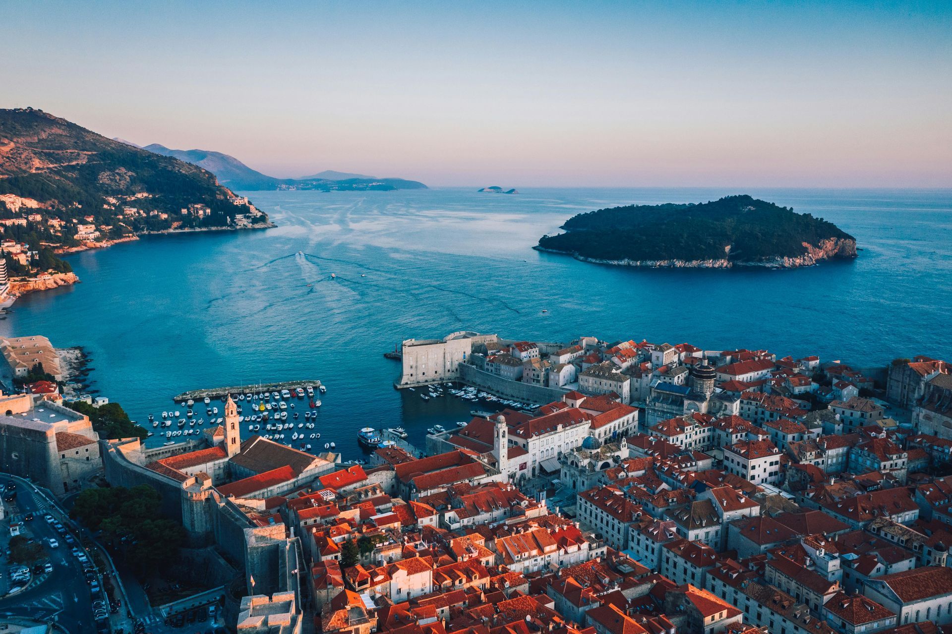 An aerial view of a city and a small island in the middle of the ocean.