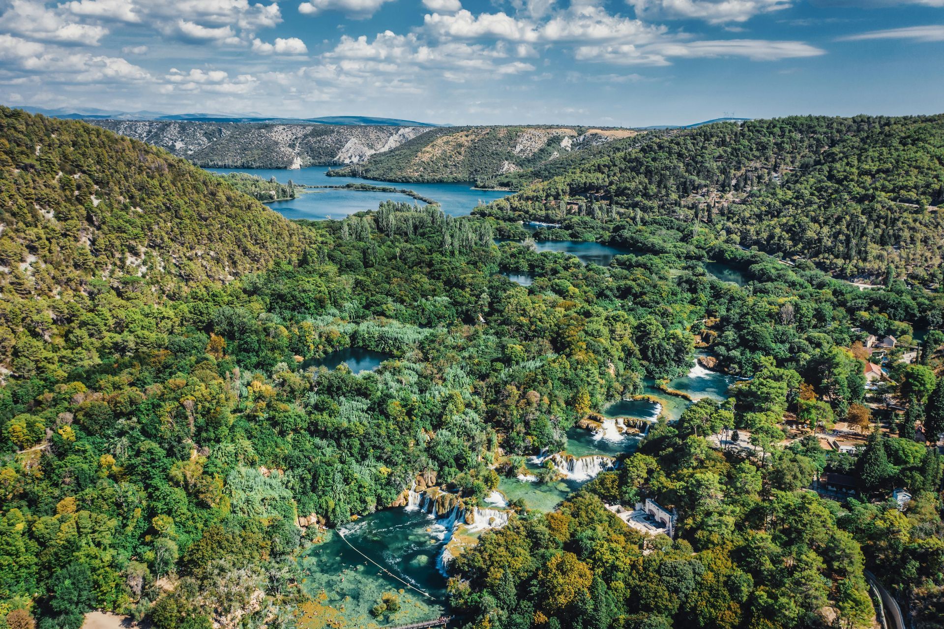 Scenic aerial view of Krka National Park in Croatia, with lush green vegetation and a blue river winding through landscape.
