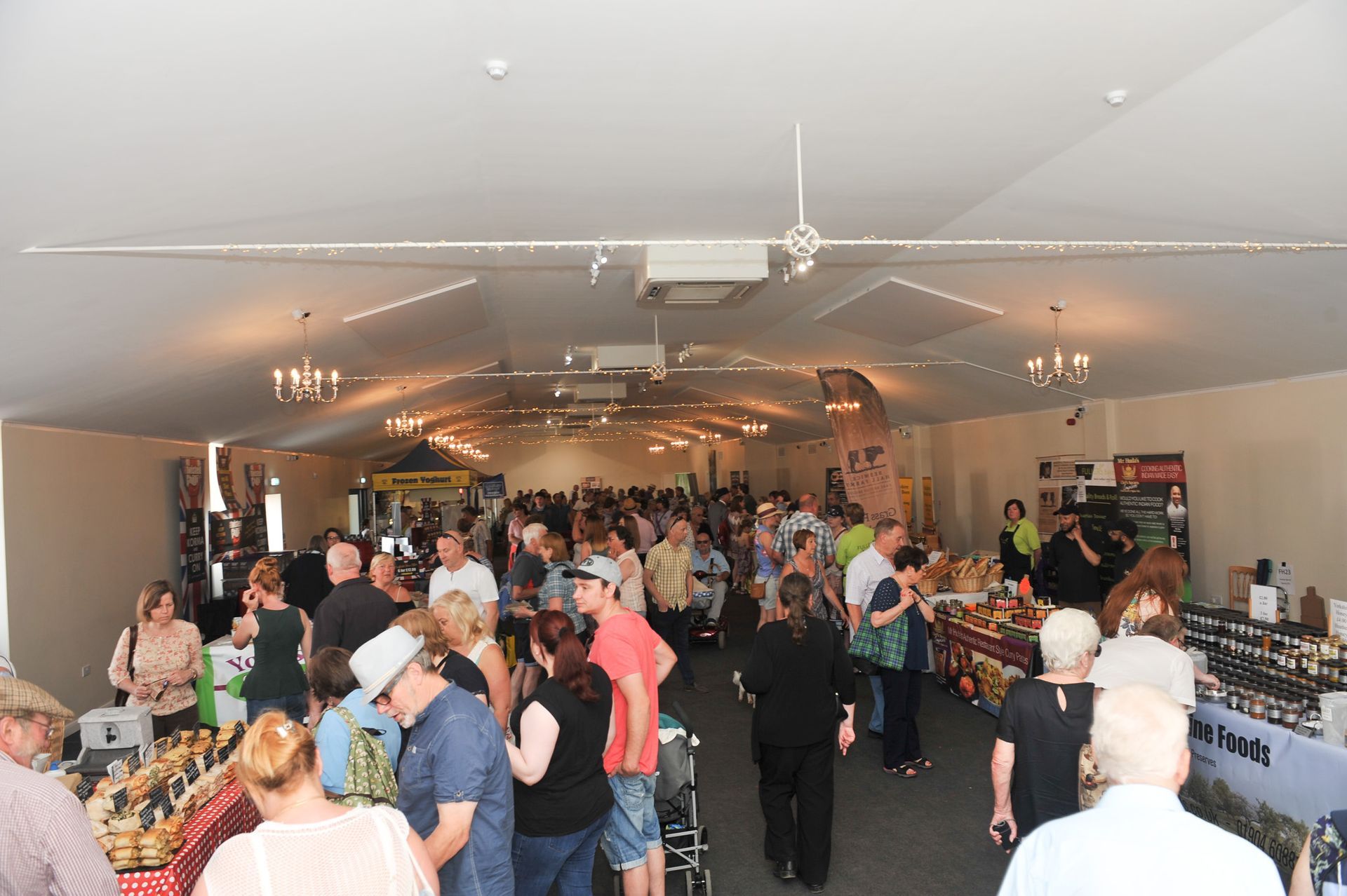 Crowded indoor event with people mingling around tables in a brightly lit hall