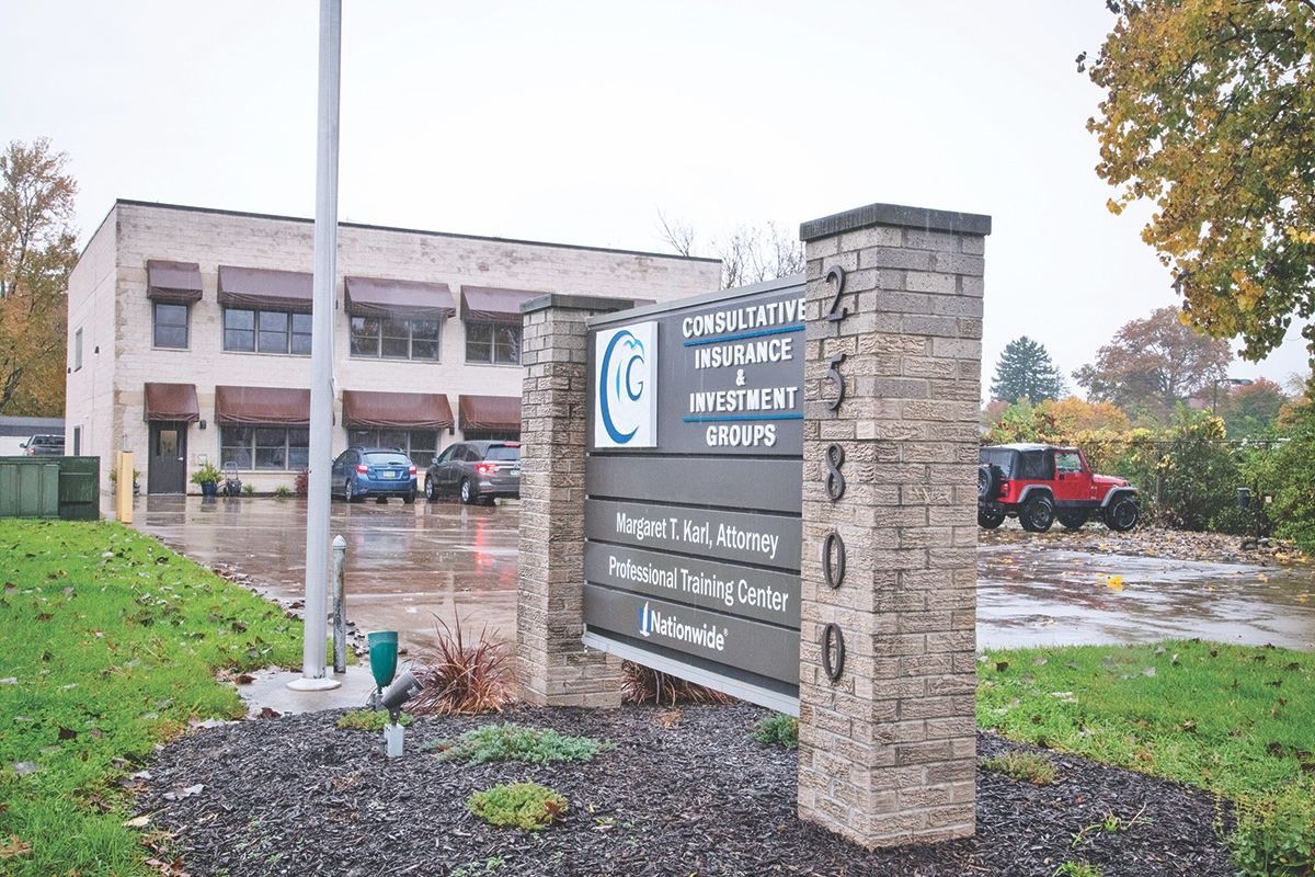 A brick-and-mortar office building with a stone monument sign reading