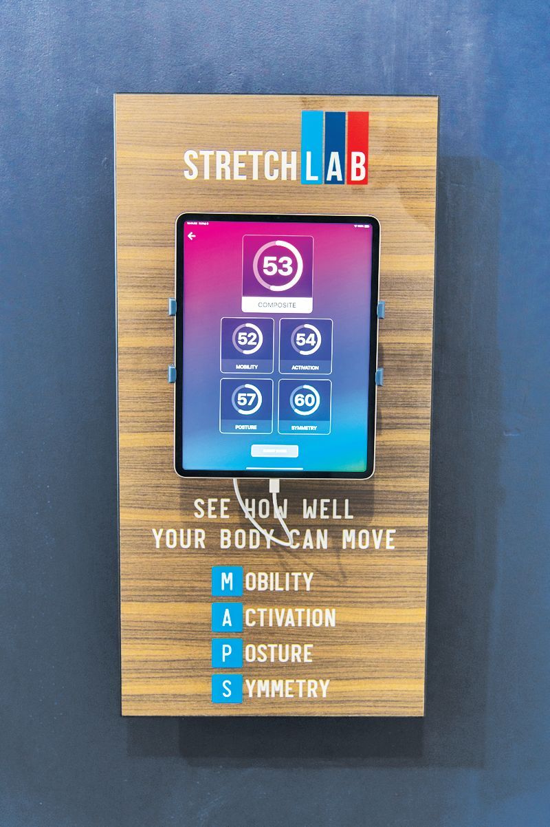 A StretchLab wall-mounted tablet display shows a 