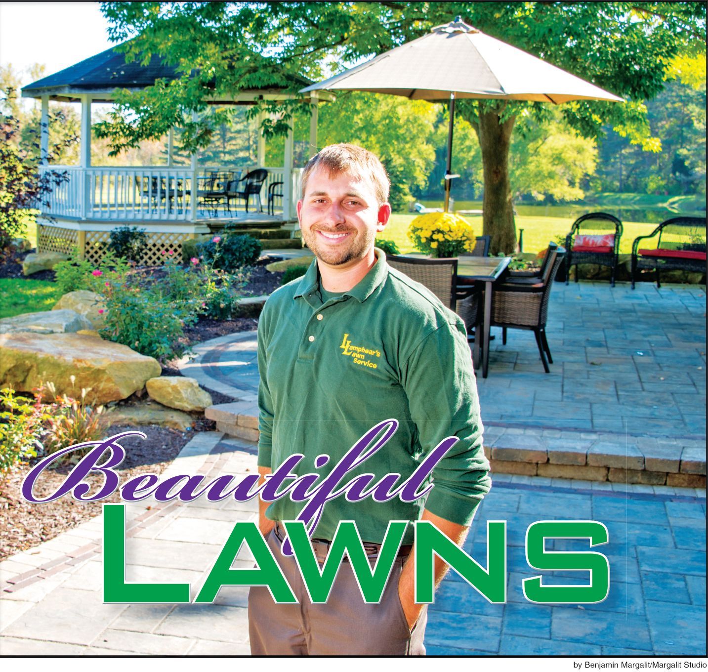 A smiling person stands in a stone patio garden with a gazebo and patio furniture in the background. Green text reads LAWNS.