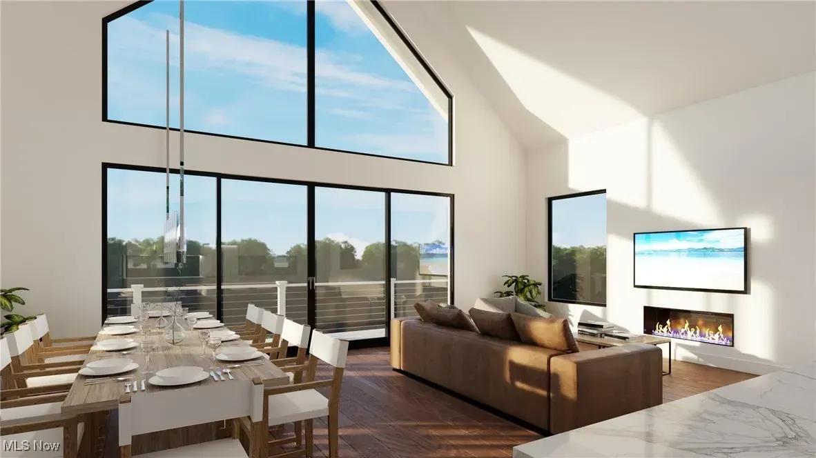 Modern open-concept living area with high ceilings, large windows, a dining table, a brown sofa, and a fireplace.