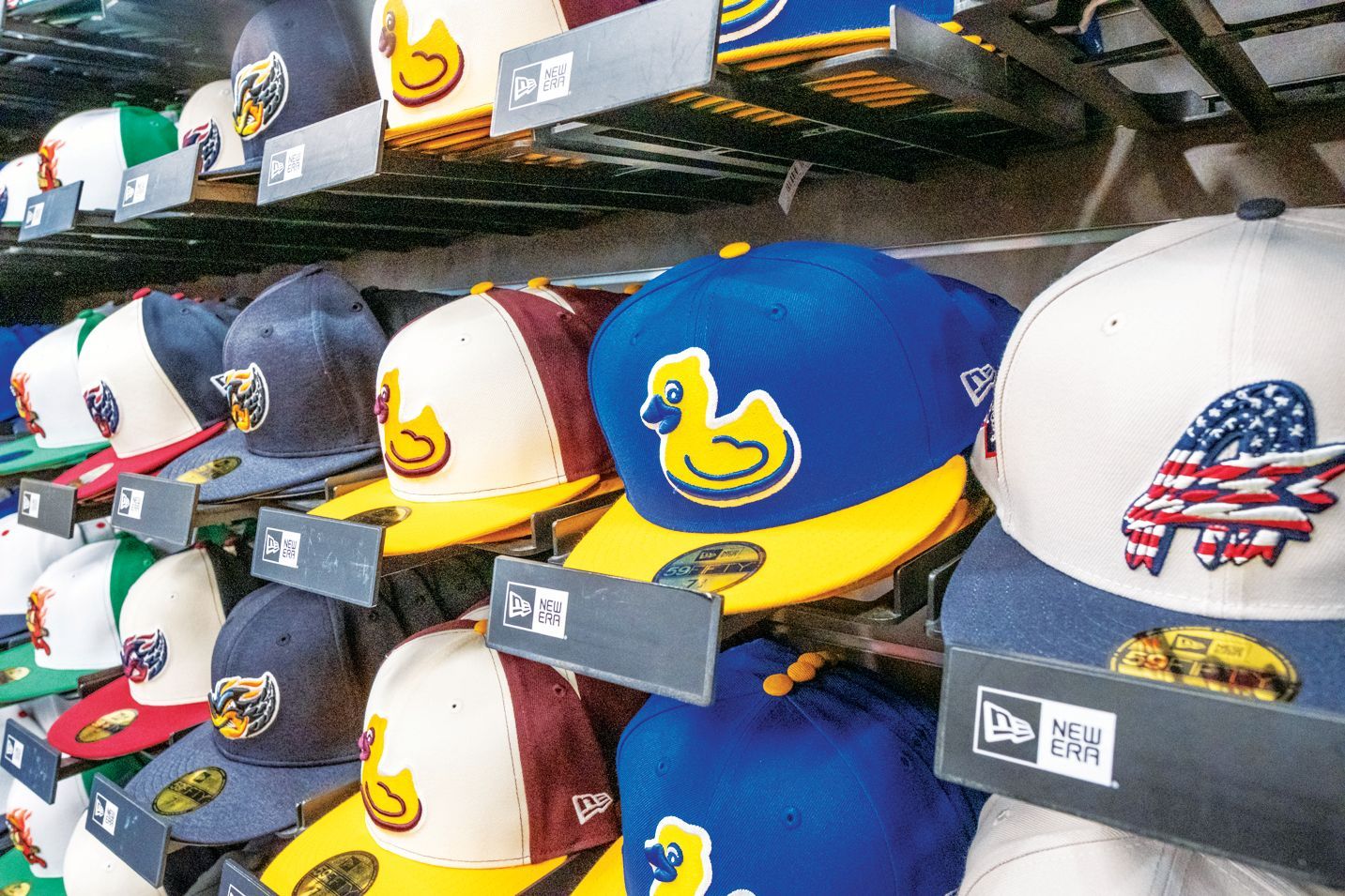 A store shelf displaying multiple baseball caps in various colors, including several with a yellow duck logo.