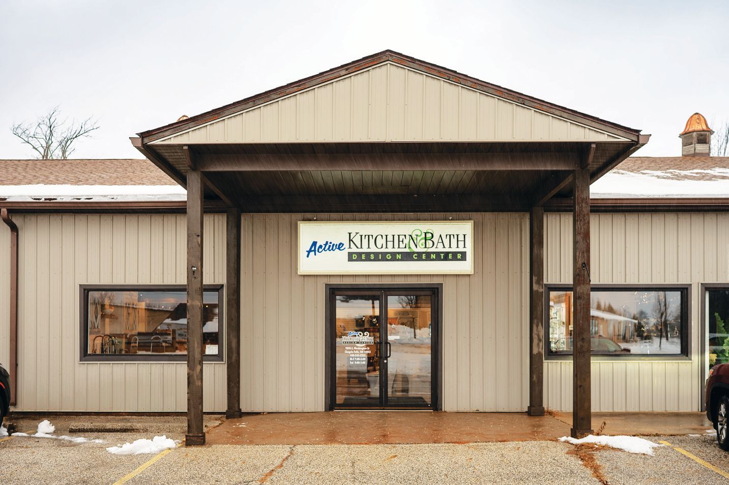 Action Kitchen & Bath Design Center storefront featuring tan vertical siding, a covered entryway, and large display windows.